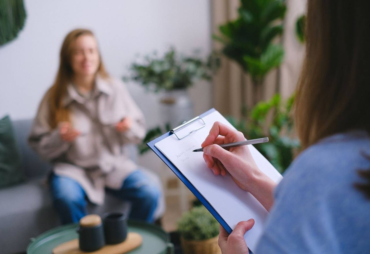 A clinician taking notes on a clipboard during a patient consultation