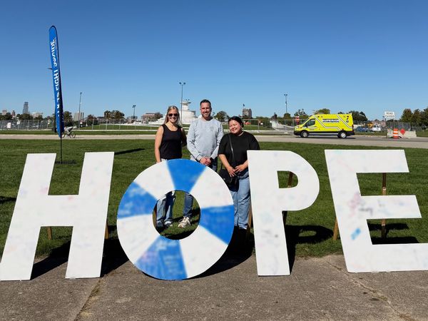 Dr. Adam Joy and two Joy Mental Health Group team members standing behind giant HOPE letters on the lawn at the Out of the Darkness Walk on Belle Isle