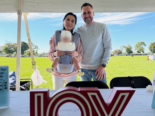 Dr. Adam Joy and a Joy Mental Health Group team member at the outreach booth with lighted JOY letters at the Out of the Darkness Walk on Belle Isle
