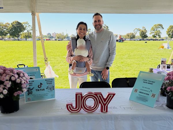 Joy Mental Health Group team members behind the outreach table with resource cards and lighted JOY letters at the Out of the Darkness Walk on Belle Isle