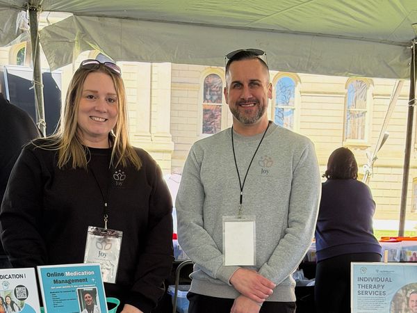 Two Joy Mental Health Group team members at the outreach tent at the UFAM Rally, with the Michigan State Capitol behind them