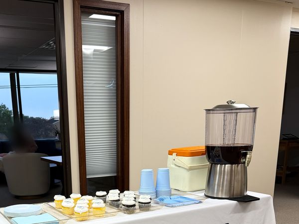 Coffee dispenser, cups and snacks set out on a table for the ribbon cutting at the Joy Mental Health Group West Bloomfield office